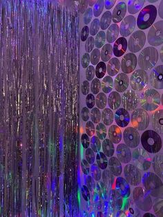 disco balls are hanging from the ceiling in front of a wall with cds on it