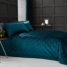 a bed with teal colored sheets and pillows