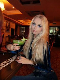 a woman sitting at a table holding a drink