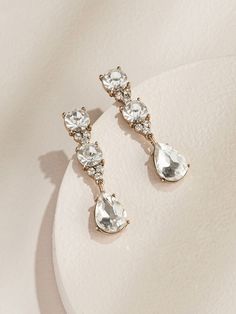 two pairs of earrings sitting on top of a white plate with an earring in the middle