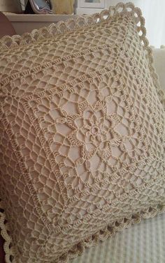 a crocheted pillow is sitting on a couch with a lace doily around it