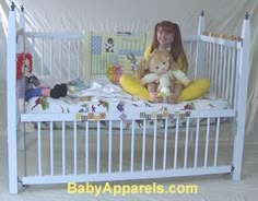 a woman sitting on top of a bed holding a stuffed animal next to a baby crib