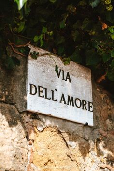 a stone wall with a sign that says via dell'amore on the side