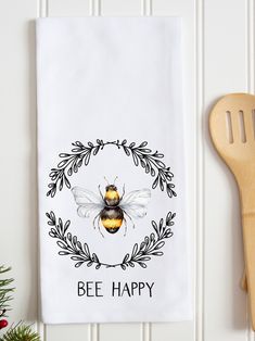 a kitchen towel with a bee on it next to a spatula and wooden utensils