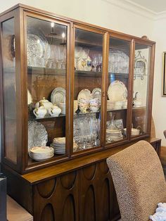 an old china cabinet with glass doors and dishes on the top, sitting in a living room