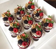 there are many cupcakes on the white plate with berries, nuts and strawberries