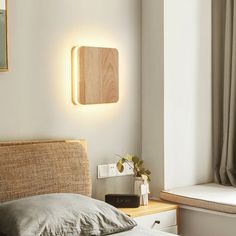 a bed with a wooden headboard and light on the wall next to a window