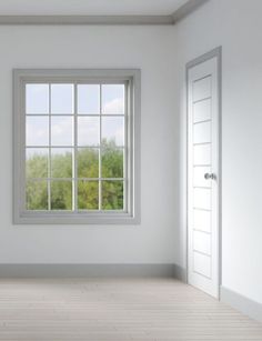 an empty room with white walls and two open doors, looking out to the trees outside