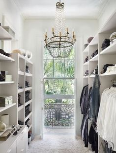 an image of a closet with clothes and other items on shelves in front of a window