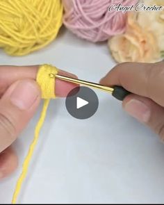 someone crocheting yellow yarn on a white surface