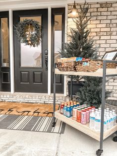 the front porch is decorated for christmas and has an outdoor cooler cart with drinks on it