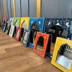 a row of colorful mirrors sitting on top of a wooden floor next to each other