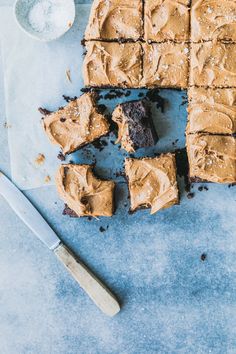 brownies with peanut butter frosting cut into squares next to a knife and spoon