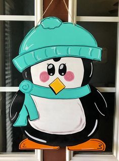 a penguin with a blue hat and scarf hanging from a door handle on the front of a house