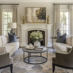 a living room with couches, chairs and a table in front of a fireplace