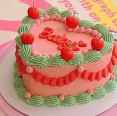 a heart shaped birthday cake with cherries on top and the word love spelled out