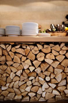 stacks of firewood stacked on top of each other in a kitchen with plates and bowls