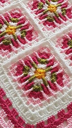 a pink and white crocheted blanket with yellow flowers on the center is shown