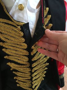 a person is holding onto a jacket with gold sequins on the front and back