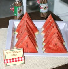 three slices of watermelon are on a white plate with a red checkered tablecloth