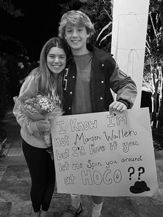 two people standing next to each other holding a sign