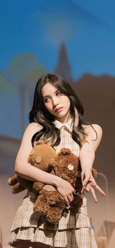 a woman holding a brown teddy bear in her hands