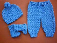 a blue knitted outfit with matching hat and booties is shown on a brown surface