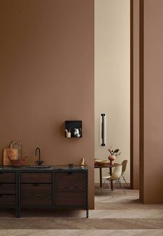 a kitchen with brown walls and wooden cabinets in the center, along with a dining room table