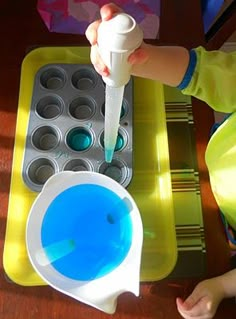 a little boy pouring blue liquid into a cup