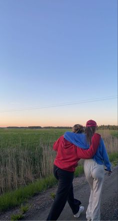 two people are walking down the road with their arms around each other and one person is holding on to his back