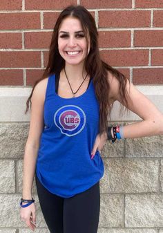 a woman standing in front of a brick wall with her hands on her hips and smiling