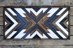 a wooden wall hanging on the side of a building with an arrow pattern painted on it