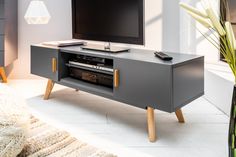 a flat screen tv sitting on top of a wooden entertainment center next to a plant