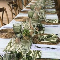 a long table set with place settings and napkins on top of each other, along with empty wine glasses