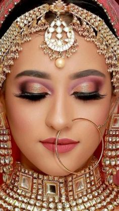 a woman wearing a red and gold bridal outfit with pearls on her head, nose ring