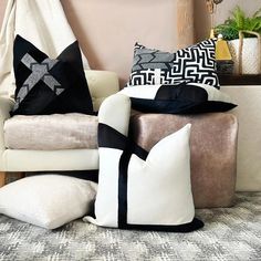 several pillows are stacked on top of each other in front of a couch with a black and white throw pillow