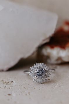 a diamond ring sitting on top of a table next to some white rocks and dirt