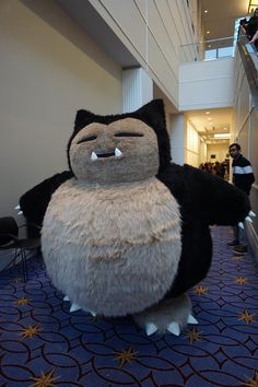 a large stuffed owl sitting on top of a blue carpeted floor next to an escalator