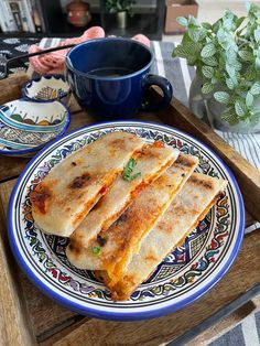 three quesadillas on a plate next to a cup of coffee