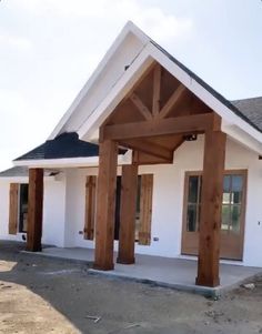 a white house with wooden pillars and windows on the front porch, in an area that is under construction