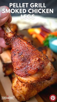 a person holding a piece of meat with the words pellet grill smoked chicken legs