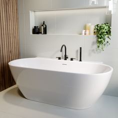 a large white bath tub sitting next to a bathroom sink with two faucets