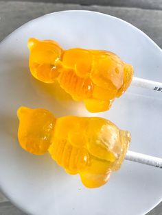 two gummy bears sitting on top of a white plate with chopsticks next to them