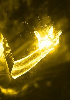 a person holding a glowing object in their hand with yellow light coming from behind it