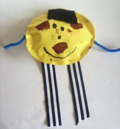 a yellow paper plate with some black sticks sticking out of it's sides and a smiling face on top