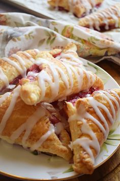 a plate topped with pastries covered in icing on top of a wooden table