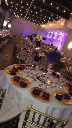 the tables are set with purple and gold place settings