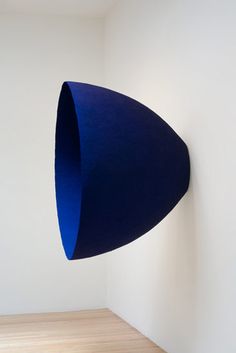 a large blue object hanging from the side of a wall in a white walled room