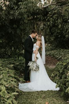 a bride and groom standing in the middle of some bushes with their backs to each other