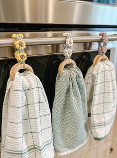 three tea towels hanging from the handle of an oven